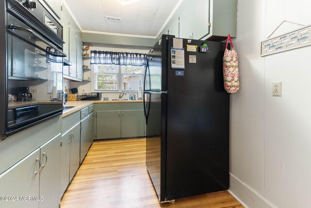 kitchen with black fridge, light hardwood / wood-style flooring, crown molding, and sink