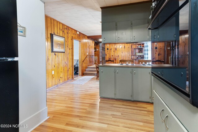 kitchen featuring wood walls, kitchen peninsula, light hardwood / wood-style flooring, and gray cabinetry