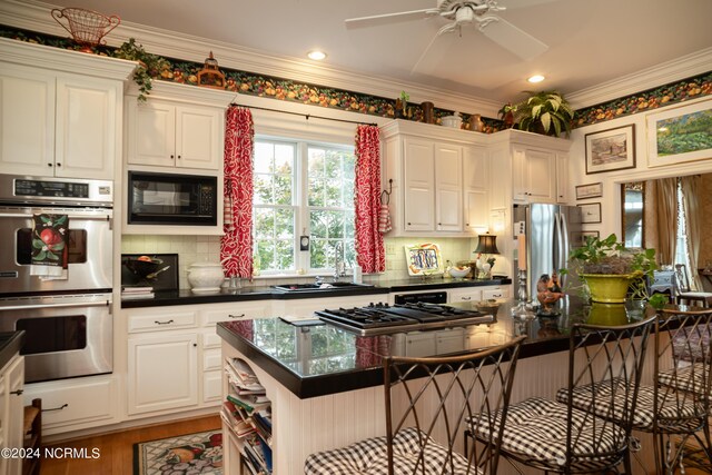 kitchen with white cabinetry, ceiling fan, tasteful backsplash, stainless steel appliances, and ornamental molding