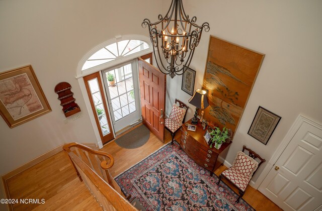 foyer entrance with a chandelier, wood-type flooring, and a towering ceiling