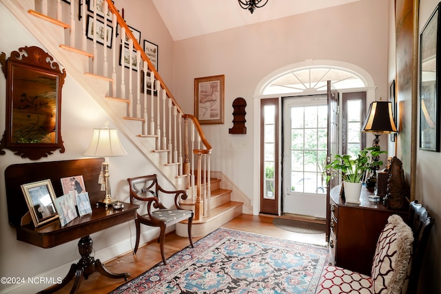 foyer featuring stairs, baseboards, vaulted ceiling, and wood finished floors