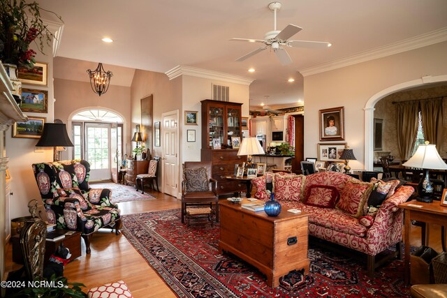 living room with ornamental molding, ceiling fan with notable chandelier, and hardwood / wood-style floors