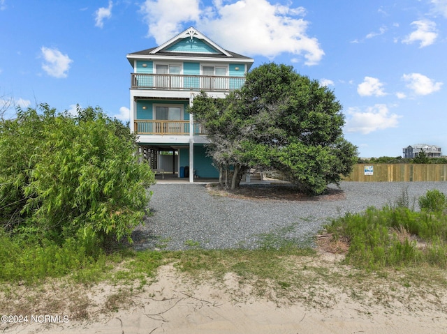 coastal home featuring driveway, a carport, and a balcony