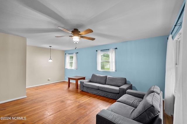 living room with light wood-style floors, ceiling fan, and baseboards