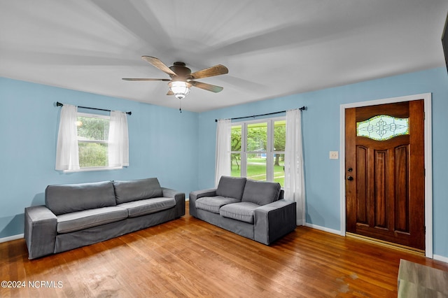 living area with a ceiling fan, plenty of natural light, baseboards, and wood finished floors