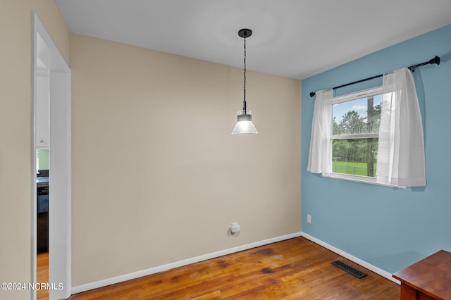 empty room featuring visible vents, baseboards, and wood finished floors