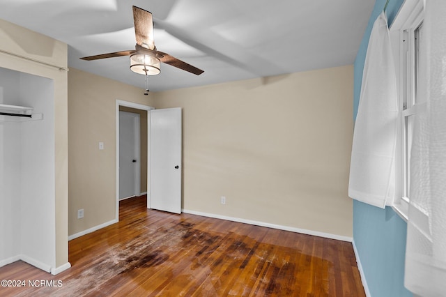 unfurnished bedroom with hardwood / wood-style flooring, a ceiling fan, baseboards, and a closet