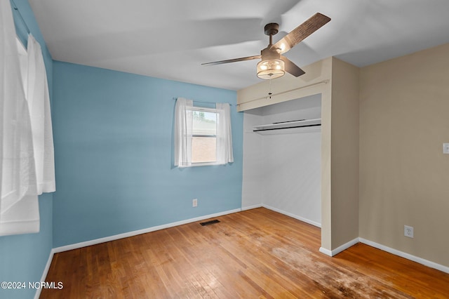 unfurnished bedroom featuring baseboards, visible vents, ceiling fan, wood finished floors, and a closet