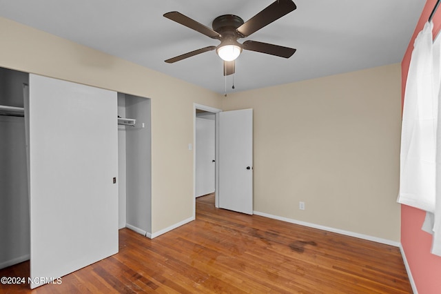 unfurnished bedroom with ceiling fan, a closet, baseboards, and wood finished floors