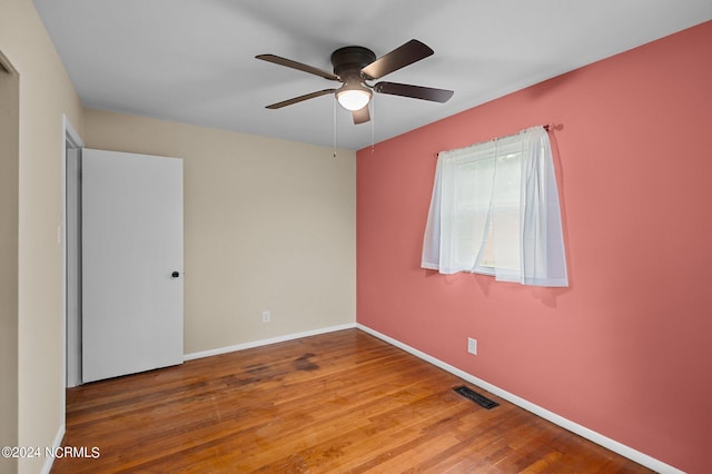 empty room featuring visible vents, ceiling fan, baseboards, and wood finished floors