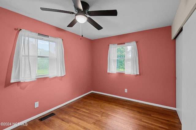 empty room with visible vents, ceiling fan, baseboards, and wood finished floors