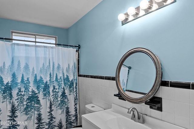 bathroom featuring a wainscoted wall, tile walls, toilet, vanity, and a shower with curtain