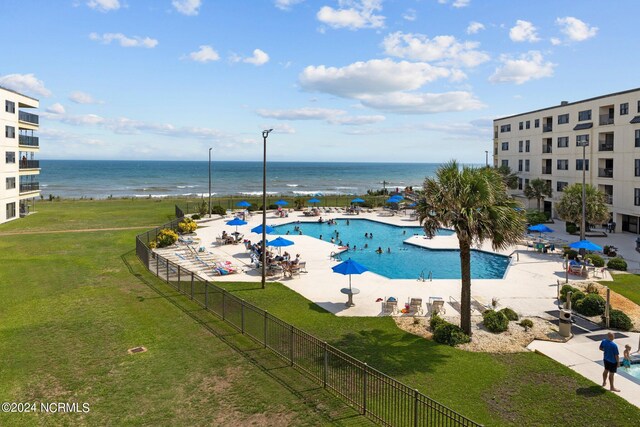 view of swimming pool featuring a lawn, a patio area, and a water view