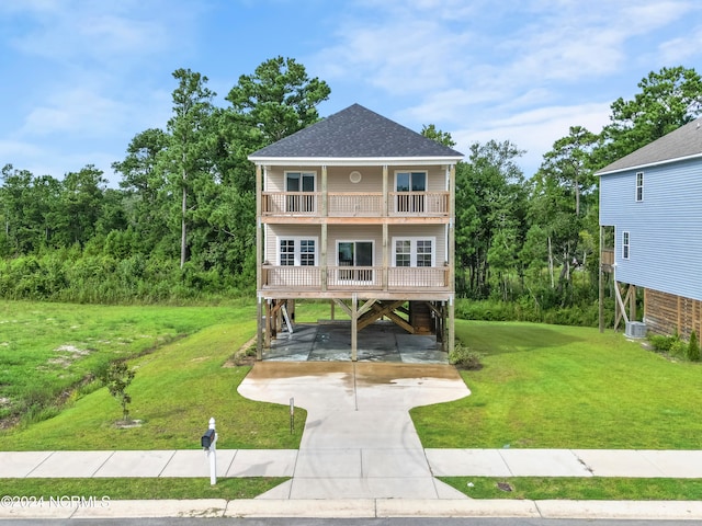 view of front of house with a carport, a balcony, central AC, and a front yard