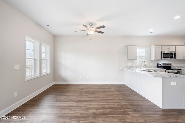 kitchen with appliances with stainless steel finishes, hardwood / wood-style flooring, sink, white cabinetry, and ceiling fan