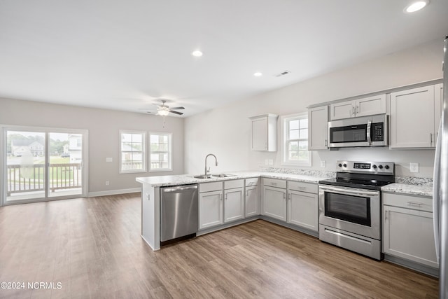 kitchen with ceiling fan, light wood-type flooring, sink, appliances with stainless steel finishes, and kitchen peninsula