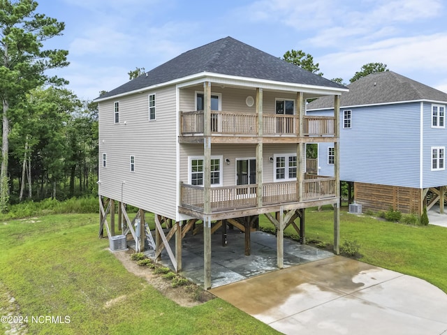 rear view of house featuring a carport, a balcony, central AC unit, and a lawn