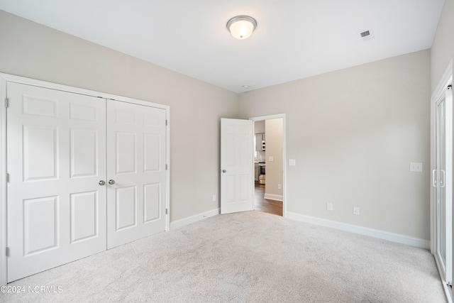 unfurnished bedroom with light carpet and a closet