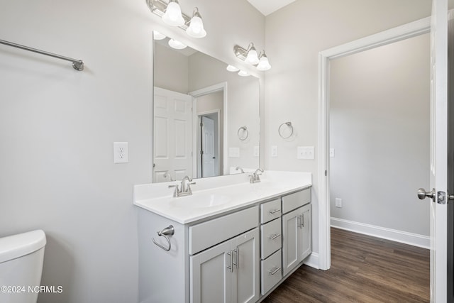 bathroom with wood-type flooring, dual vanity, and toilet