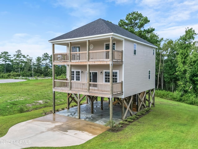 rear view of house featuring a carport, a balcony, and a lawn