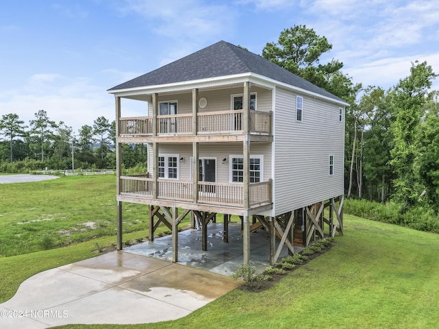 rear view of property featuring a carport, a balcony, and a yard