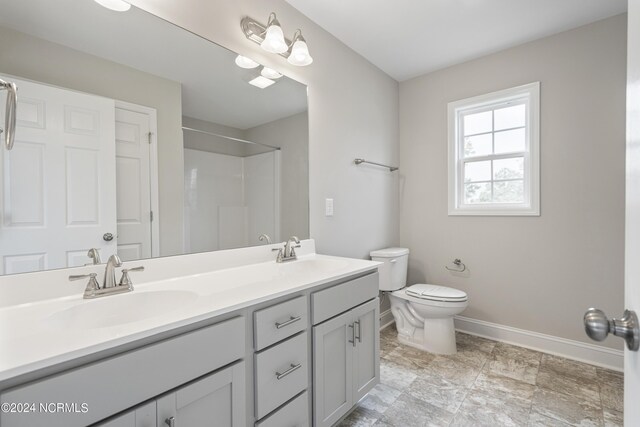 bathroom with dual vanity, toilet, and tile patterned floors