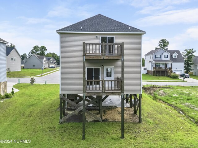 back of property with a balcony, a garage, and a lawn