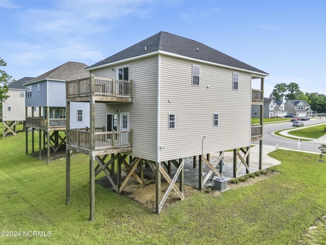 rear view of house with cooling unit and a lawn