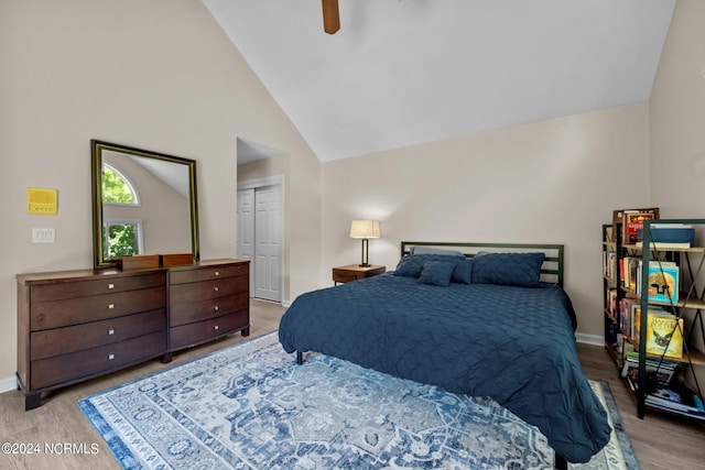 bedroom featuring high vaulted ceiling, light wood-type flooring, a closet, and ceiling fan