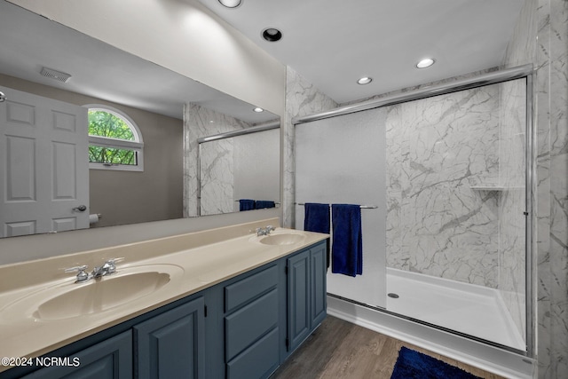 bathroom with dual vanity, a shower with door, and hardwood / wood-style flooring