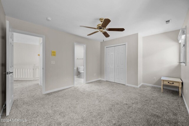 unfurnished bedroom featuring ceiling fan, connected bathroom, light carpet, and a closet