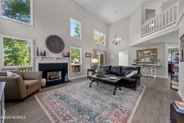 living room with a tile fireplace, a towering ceiling, hardwood / wood-style flooring, and a notable chandelier