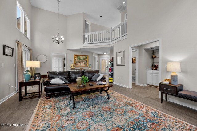 living room with a towering ceiling, hardwood / wood-style floors, and a chandelier