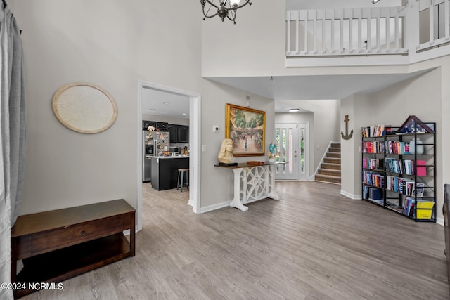 interior space with a notable chandelier, hardwood / wood-style flooring, and a high ceiling