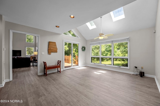 living room with ceiling fan, wood-type flooring, a skylight, and high vaulted ceiling