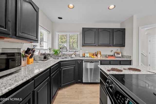 kitchen featuring light wood-type flooring, appliances with stainless steel finishes, sink, and light stone countertops