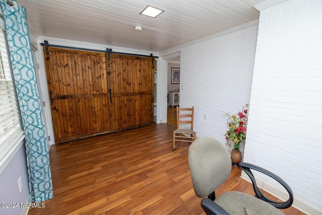 office area featuring brick wall, wood-type flooring, a barn door, and ornamental molding