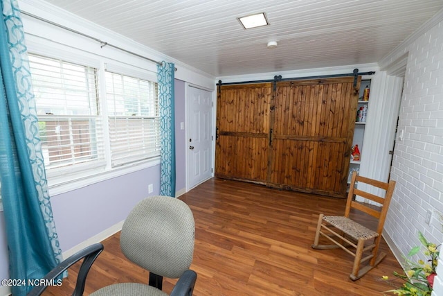 living area with wood-type flooring, ornamental molding, a barn door, and brick wall