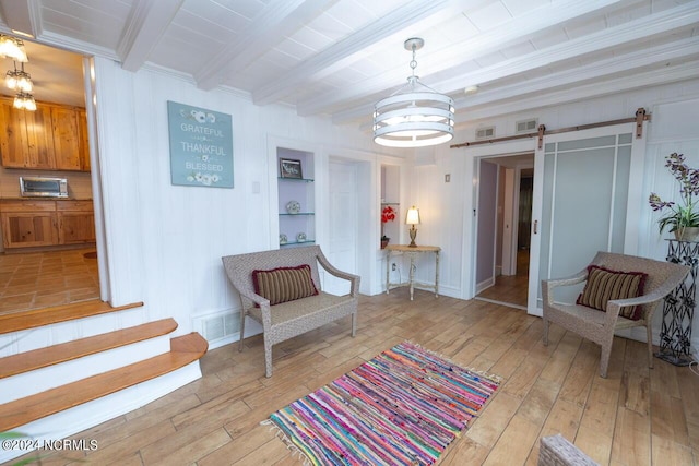 sitting room with light wood-type flooring, a notable chandelier, crown molding, a barn door, and beam ceiling