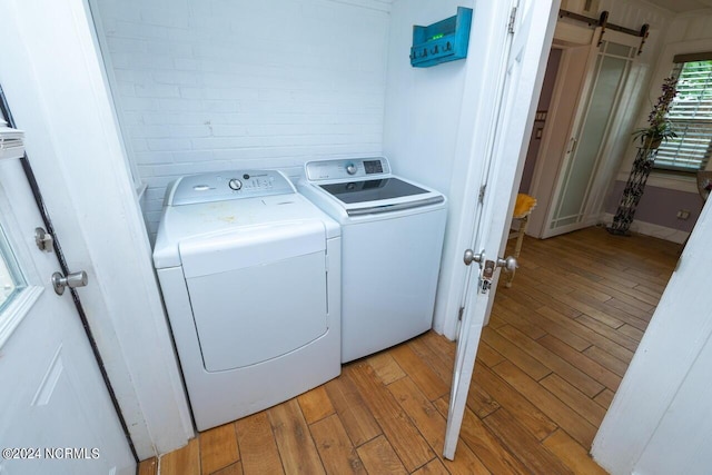 clothes washing area with independent washer and dryer, a barn door, and light hardwood / wood-style flooring