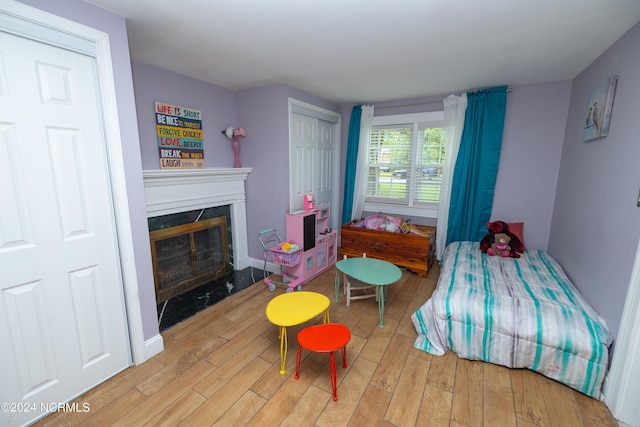 bedroom with light hardwood / wood-style floors and a premium fireplace