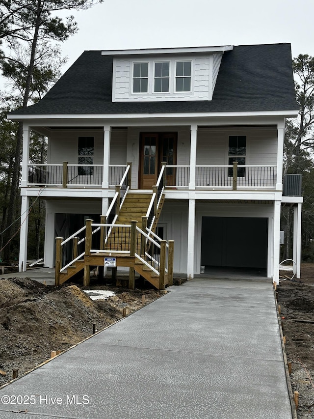 raised beach house featuring a porch, concrete driveway, a shingled roof, and stairway