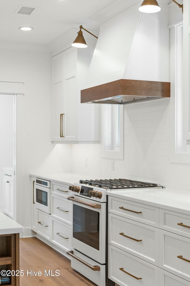 3404 Eagle Crest Dr SW, Supply, NC 28462 - kitchen with white range with gas stovetop, wall chimney range hood, light wood finished floors, tasteful backsplash, and light countertops