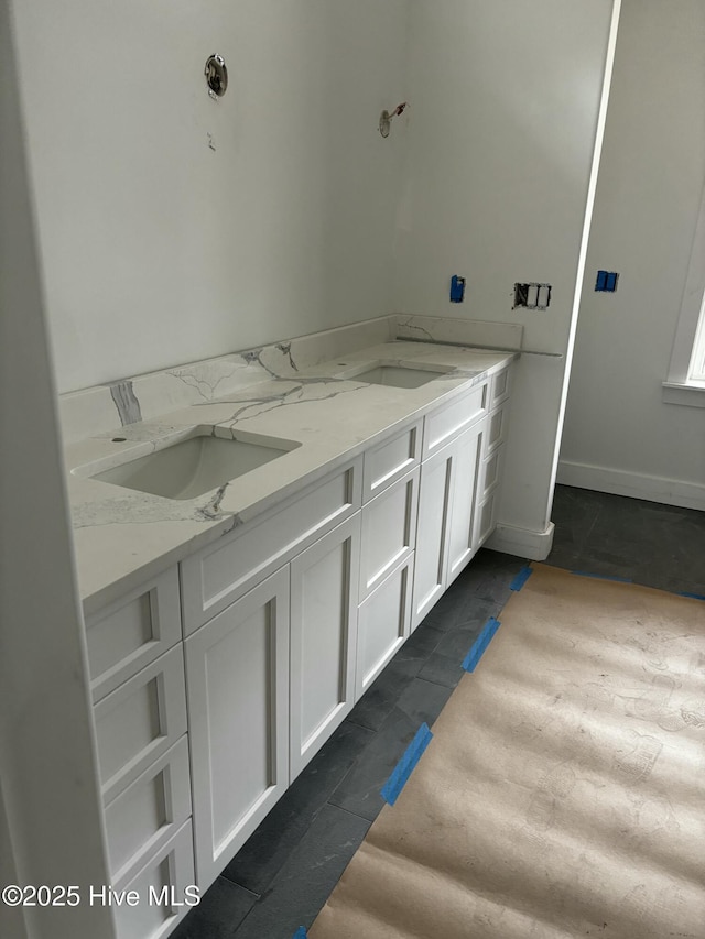 full bathroom featuring double vanity, baseboards, a sink, and tile patterned floors