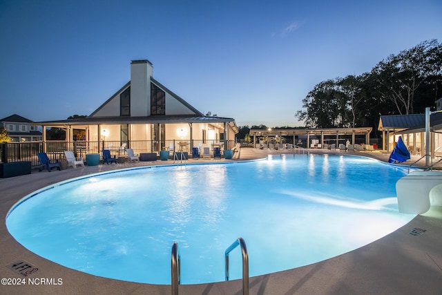 pool at dusk featuring a patio