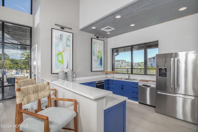 kitchen with blue cabinetry, sink, a healthy amount of sunlight, stainless steel appliances, and kitchen peninsula