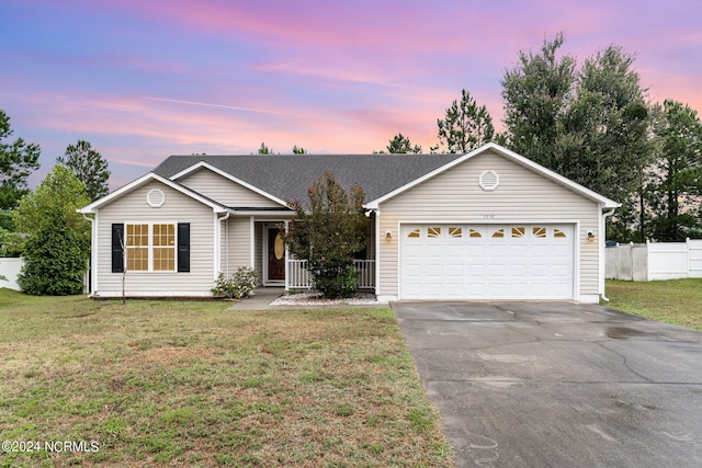 ranch-style house featuring a garage and a yard