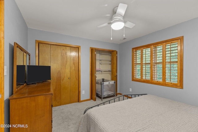 bedroom with carpet, ceiling fan, and two closets