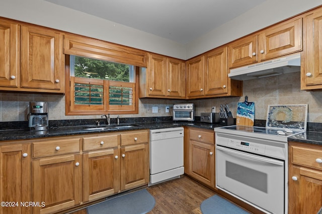 kitchen with decorative backsplash, white appliances, dark wood-type flooring, sink, and dark stone countertops