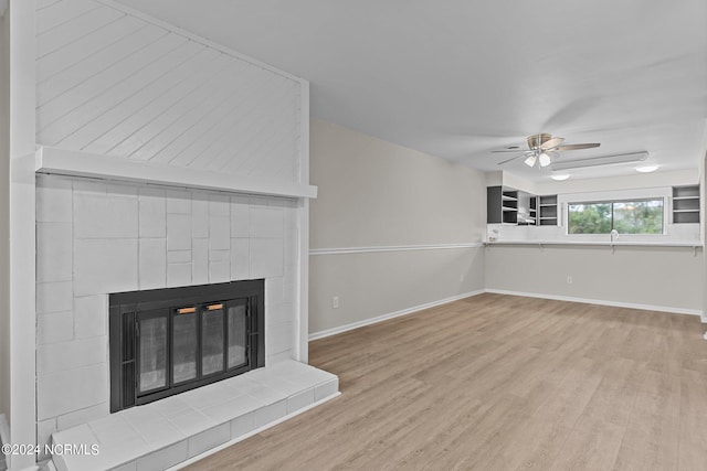 unfurnished living room with a large fireplace, light hardwood / wood-style flooring, and ceiling fan